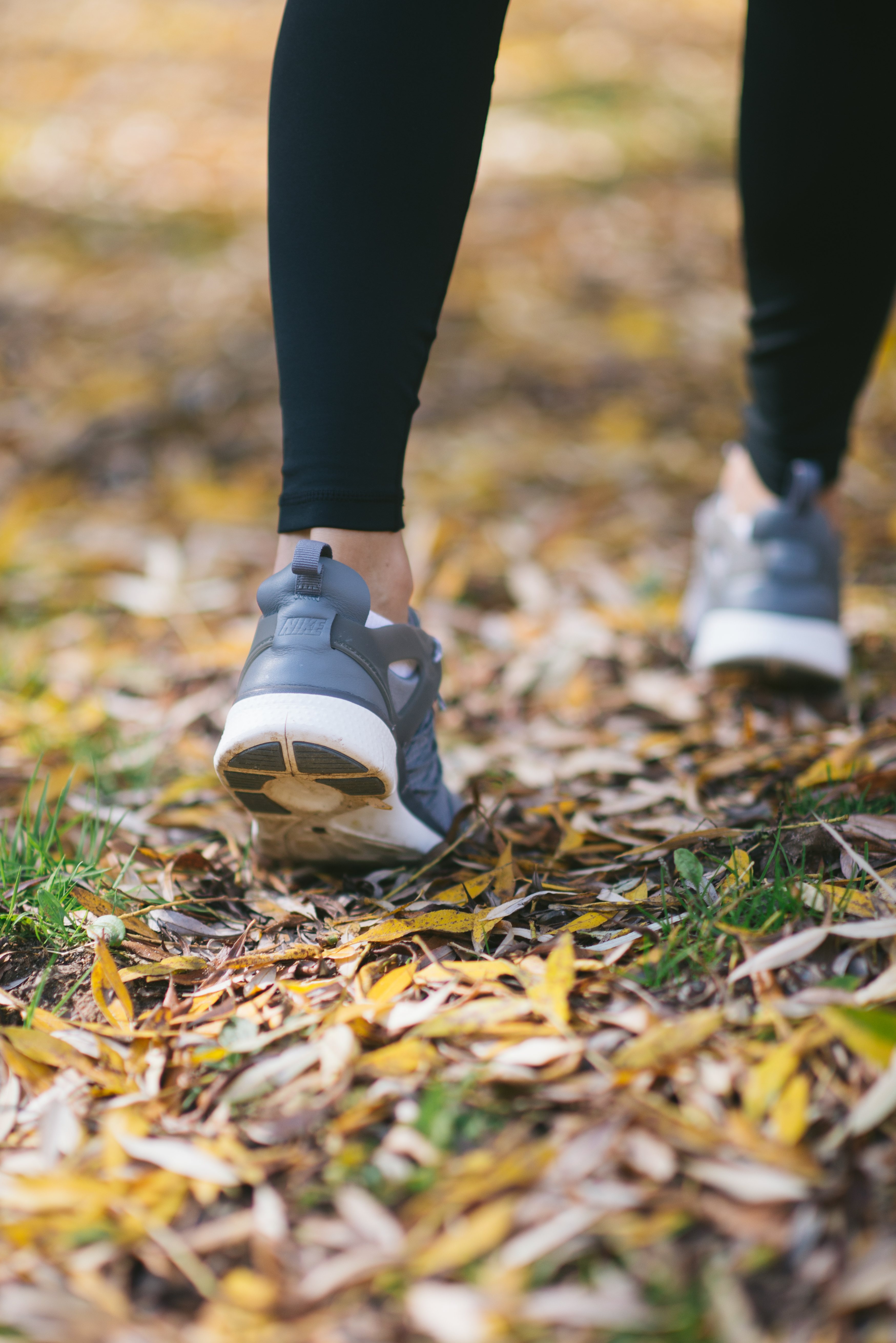 Close-up of the womans shoes and leaves on the ground.